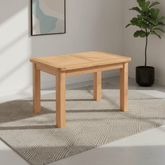 A light natural wood Chatsworth Oak rectangular table with four legs, shown in a styled room setting on a textured gray rug with a potted plant and framed wall art in the background.