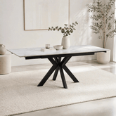 Modern dining table with marble top and black metal legs in a minimalistic room.