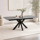 Dining table with black metal legs in a minimalistic room with plants and books.