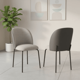 Two modern Cartier dining chairs in a minimalist room setting, one upholstered in light gray fabric and the other in dark charcoal gray, both with black metal legs.