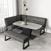 A modern dining set featuring a gray faux-leather corner banquette, a matching bench, and a gray stone-look oval table with a black pedestal base, styled in a bright contemporary dining room.
