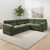 An L-shaped sectional sofa upholstered in textured sage green fabric, styled in a modern living room setting