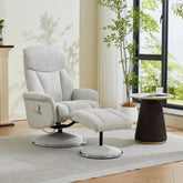 A light gray upholstered recliner chair with matching ottoman in a bright, modern living room setting with a window, potted plant, and side table.