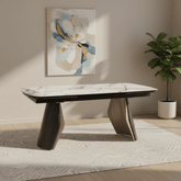 Modern dining table with marble top and wooden legs in a room with abstract art and plant.