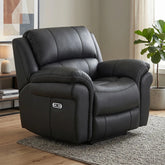 A black leather recliner chair with a power control panel on the side, shown in a styled living room setting on a gray rug.