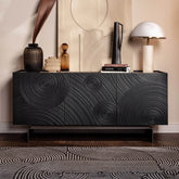 Black textured sideboard with decorative items against a beige wall.