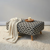 Modern upholstered footstool with mid-century design.