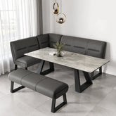 Modern corner banquette dining set with a gray faux-leather L-shaped bench, matching bench, and a rectangular marble-patterned table with black metal legs, styled in a bright dining room.