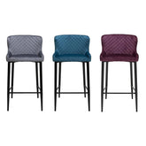 Mossley quilted bar chairs in soft fabric with 71cm seat height. Modern black legs, stitched texture, and curved comfort. Set of 2 in Blue, Grey, or Mulberry.