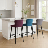 styled in a room Mossley quilted bar chairs in soft fabric with 71cm seat height. Modern black legs, stitched texture, and curved comfort. Set of 2 in Blue, Grey, or Mulberry.