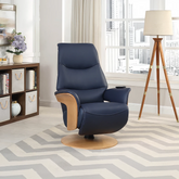 Olay Olaf navy blue leather swivel recliner chair with light wood armrests and a round wooden base, shown in a modern living room setting with a chevron rug, tripod floor lamp, and bookshelf.