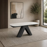 Modern dining table with black legs and white top in a room with a painting and plant.