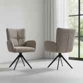 Two beige armchairs with black metal legs in a room with a window and curtains.