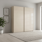 Champagne wardrobe with sliding doors in a modern room with a plant and framed art.