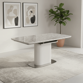 Dining table with marble-like surface in a room with abstract art and a plant.