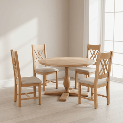 A 5-piece dining set featuring a Chatsworth round wooden table and four matching chairs with light beige upholstered seats, shown in a bright, modern room with natural light.