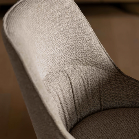 Close-up of a textured upholstered chair back in a warm taupe-beige fabric, showing the woven material and curved back shape.