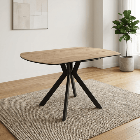 A modern oval dining table with a light oak wood grain effect sintered stone ceramic  top and a black three-legged metal base, 