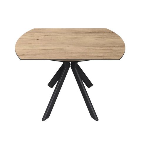 A modern oval dining table with a light oak wood grain top and a black three-legged metal base, shown on a solid white background.