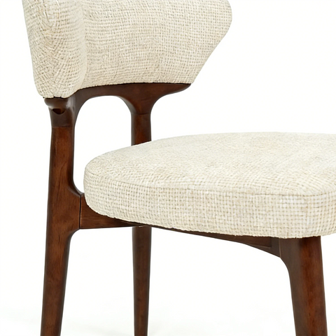 Close-up of a chair with wooden legs and beige cushioned seat and backrest on a white background