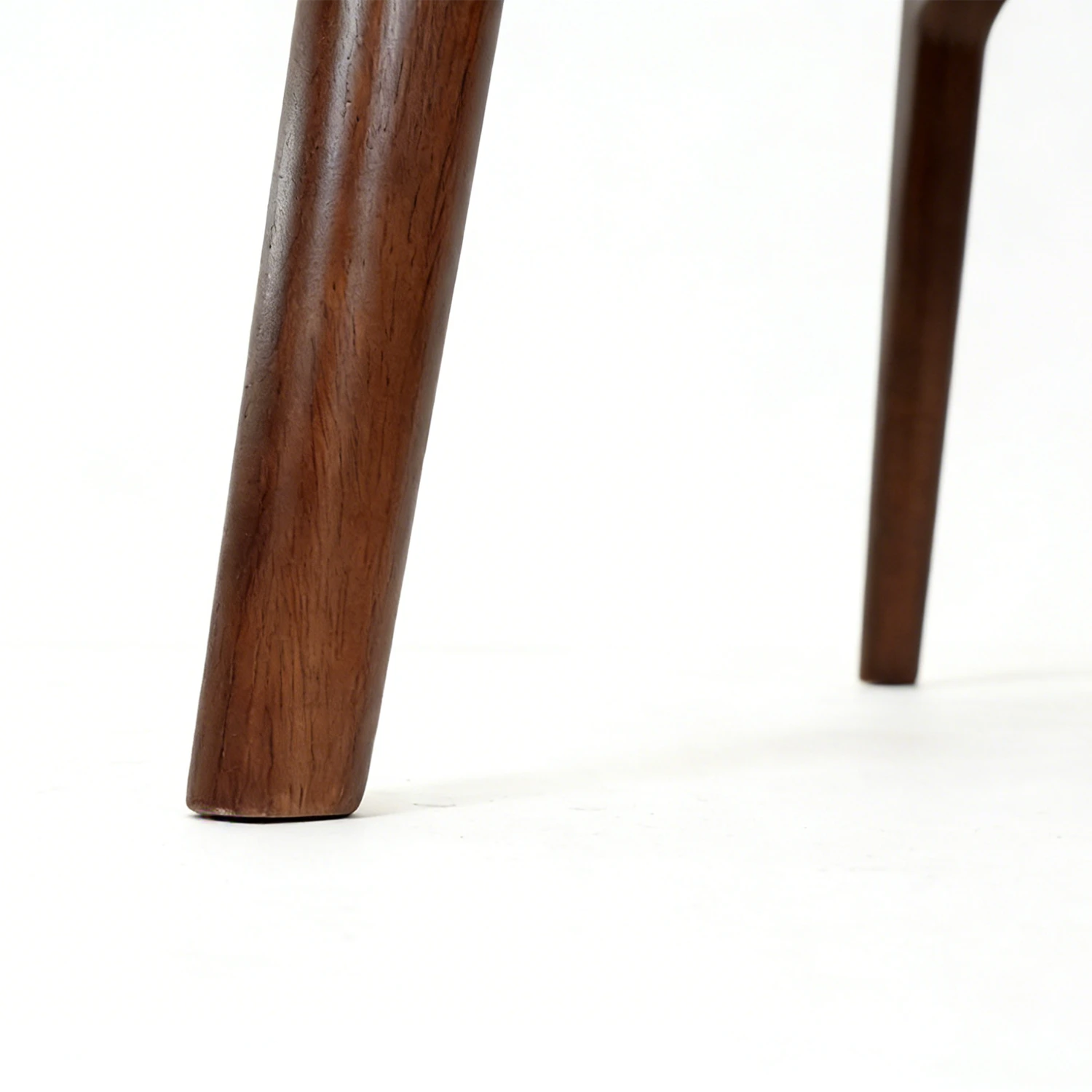 Close-up of a wooden leg Antonio dining chairs in walnut and cream set