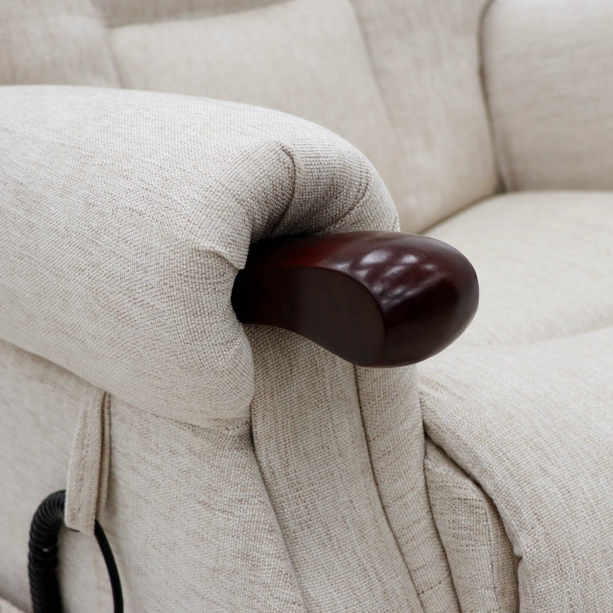 Close-up of a beige upholstered Rise recliner chair showing the armrest with a glossy dark brown wooden accent and part of a black control cord.