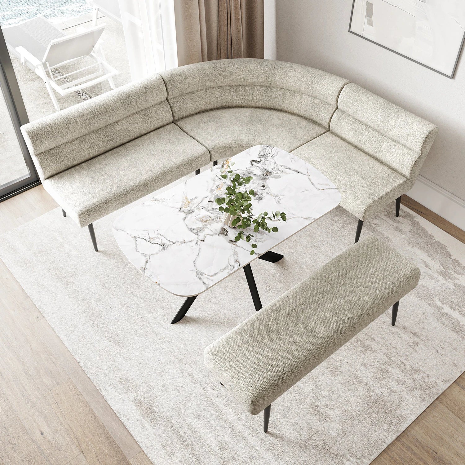 A curved upholstered seating set in a bright living room, featuring a U-shaped sofa, a matching rectangular bench, and a white marble-top coffee table with black legs on a light rug.