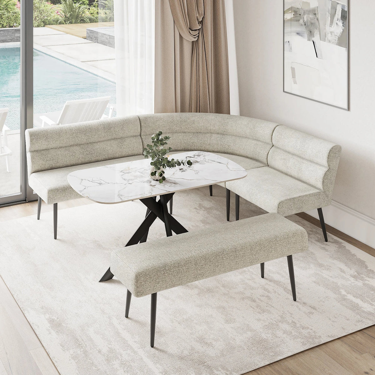 A modern curved upholstered banquette seating set with a matching bench, arranged around a round white marble-top table in a bright dining or lounge area with a window, pool view, and light rug.