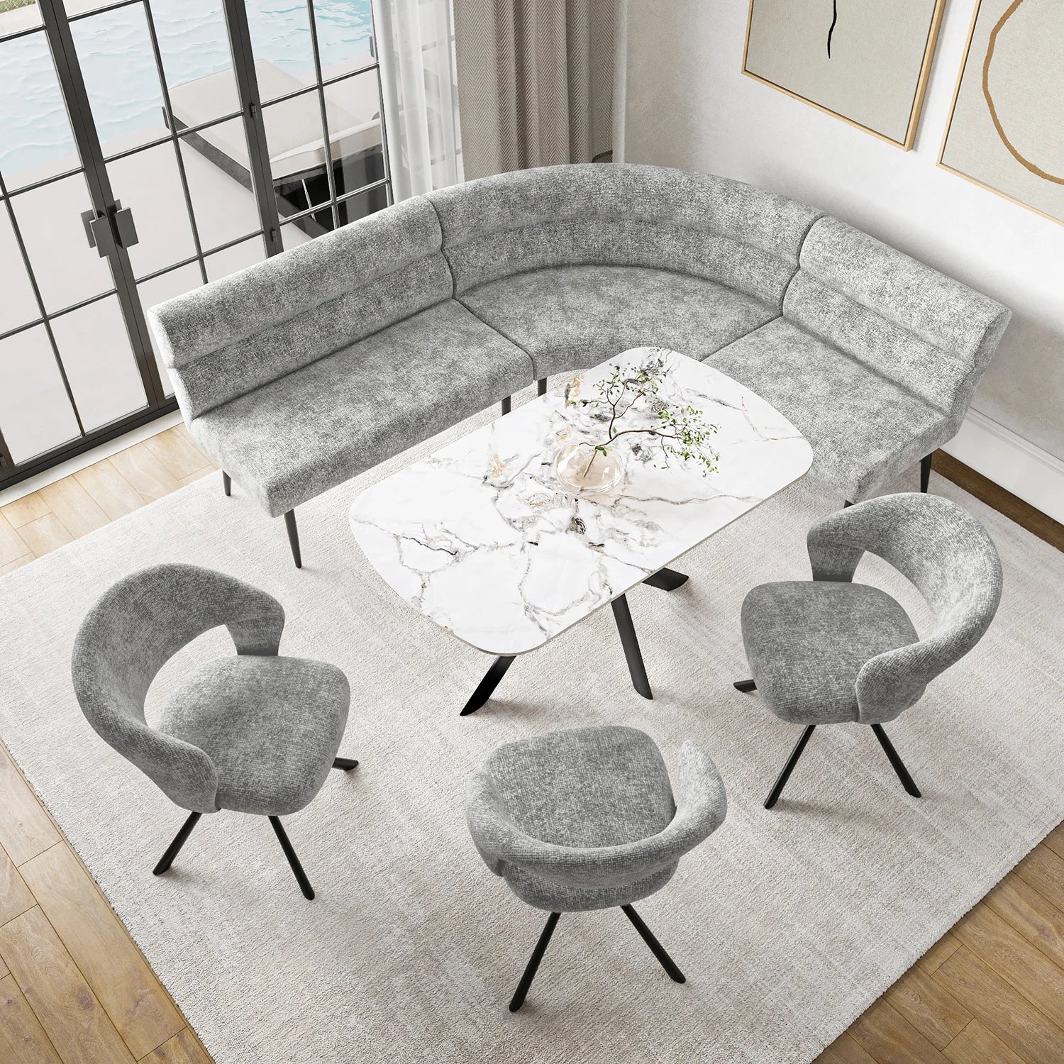 A modern curved gray upholstered dining sofa bench set with three matching gray accent chairs and a white marble-top coffee table, arranged on a light rug in a bright living room.