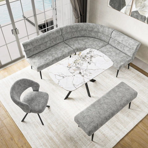 A modern living room furniture set featuring a curved gray upholstered sectional sofa, a matching gray armchair, a rectangular gray bench, and a white marble-top coffee table with black legs, arranged on a light rug.