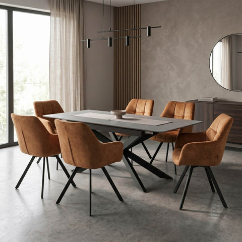 A modern dining room setup featuring a rectangular white stone dining table surrounded by six contemporary armchairs upholstered in warm camel brown velvet with black metal legs. The room has a textured beige plaster wall, a large window on the left, and a round wall mirror.