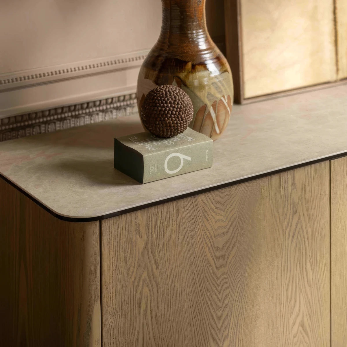 Close up of Arlo Cream Ceramic 3 Door Sideboard with push-to-open doors, sculptural ash wood legs and a stone-inspired ceramic top. 