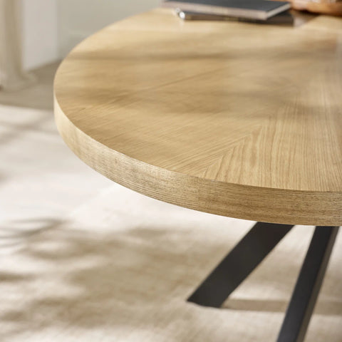 Oval wooden table with black metal legs on a light background
