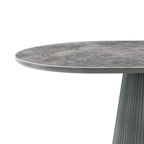 Close-up of a Bellagio Grey Sintered Stone Dining Table with Fluted Pedestal Base with a gray stone-look top and a fluted pedestal base, shown on a white background.