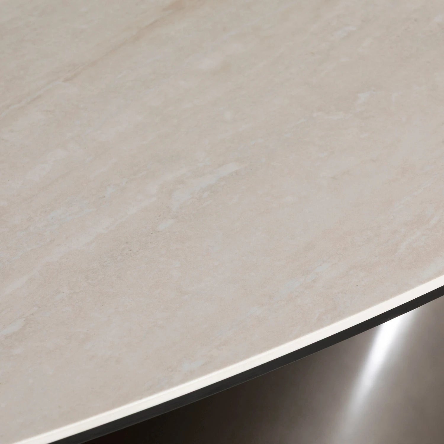 Close-up of a beige ceramic top of Brann oval dining table showcasing ceramic top and metal base