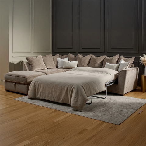 Luxury Buoyant Caspian Marlon taupe corner sofa-bed with plush scatter cushions and sleek dark wood feet.