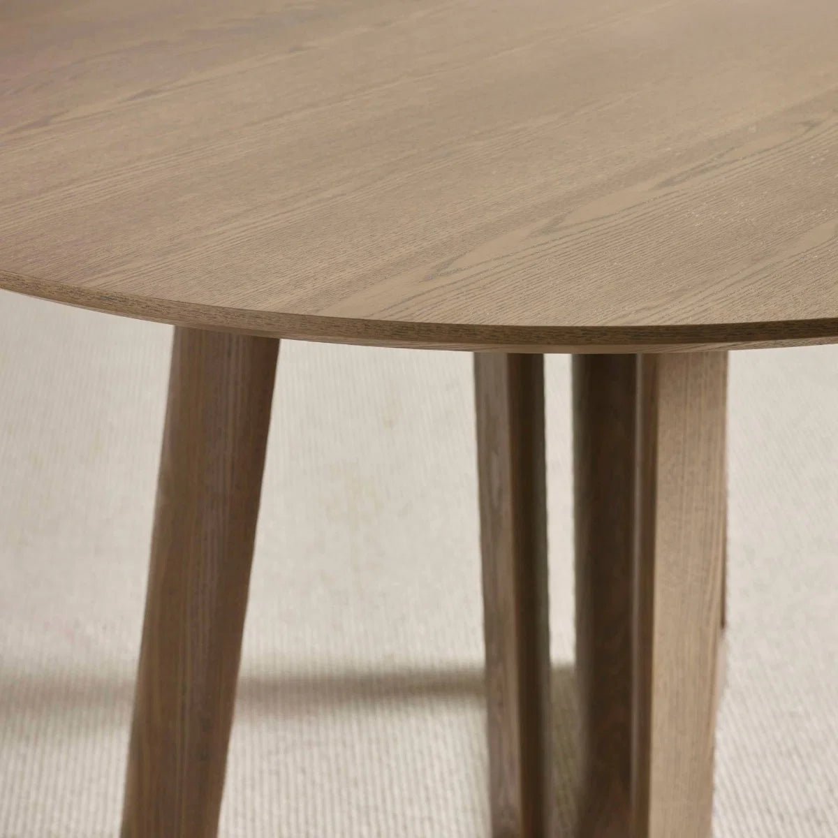 Table top of Cara 120cm Smokey Oak Effect Round Dining Table. Featuring a warm wood-effect finish, sculptural architectural base and elegant circular top.