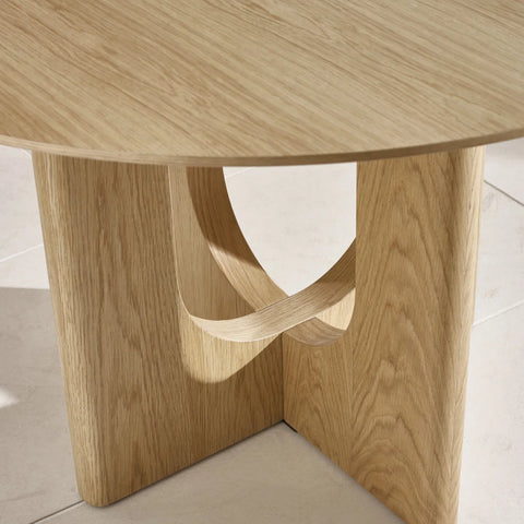 Cove Wooden round dining table with a unique base design on a light background
