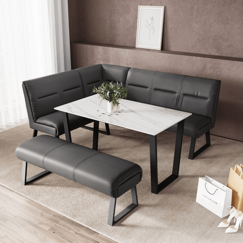 A modern 5-piece cafe dining set featuring a white marble-patterned rectangular table with black metal legs, a matching black faux-leather 3-seater bench, and a separate black bench. The set is styled in a living room setting with a brown textured wall, a beige rug, and a small potted plant on the table.