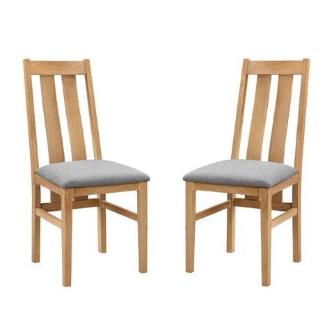 Two wooden dining chairs with light gray upholstered seats, shown side by side on a plain white background.