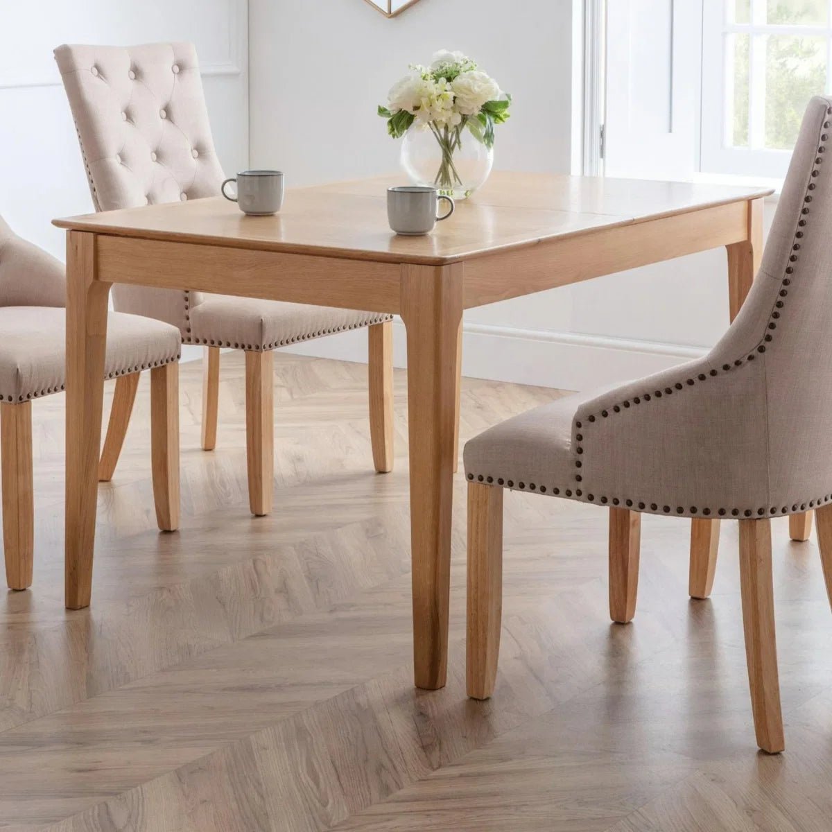 Cotswold Oak Extending Dining Table with 4 or 6 Loire Oatmeal Linen Button Back Chairs. Elegant upholstered seating and a 140-180cm oak table.
