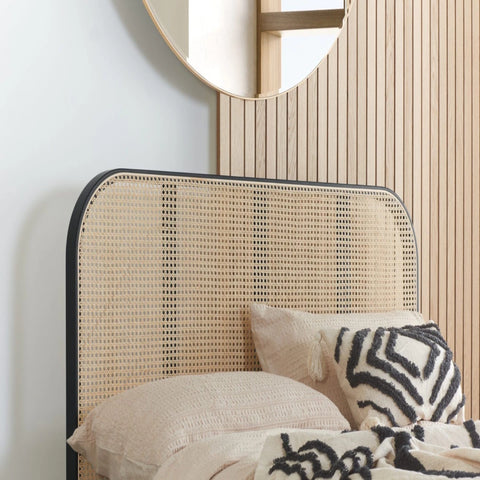 Curved rattan headboard with elegant black frame contrast.
