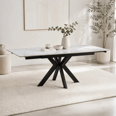 Modern dining table with marble top and black metal legs in a minimalistic room.