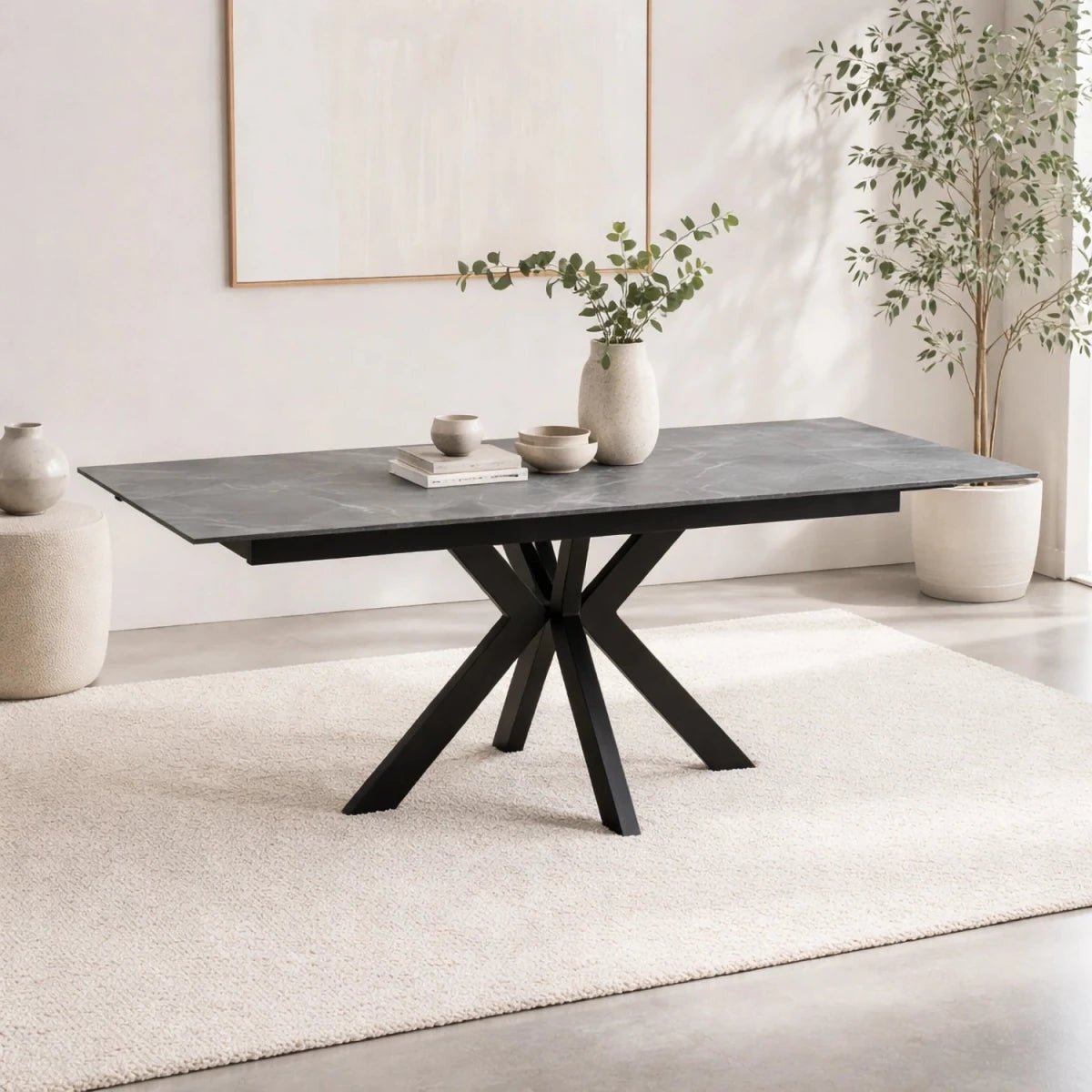 Dining table with black metal legs in a minimalistic room with plants and books.