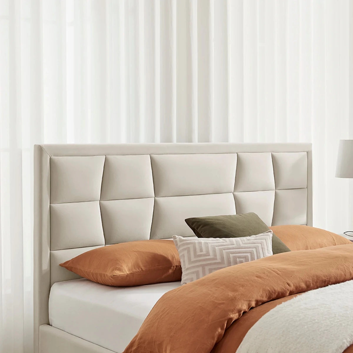 A modern upholstered bed frame with a large segmented tufted headboard in a natural/cream tone. Also available in Silver or Navy.