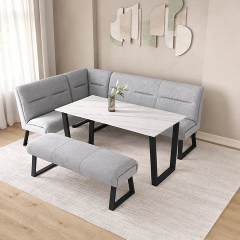 A modern L-shaped corner banquette seating set with a matching bench, featuring light gray upholstered cushions and black metal legs, arranged around a white marble-patterned rectangular table in a styled dining room setting.