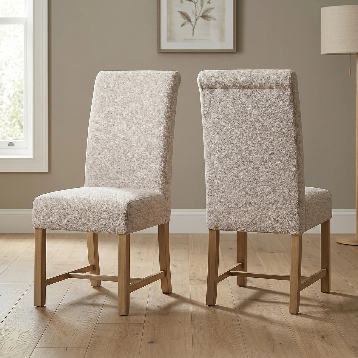Two beige upholstered chairs with wooden legs on a wooden floor.