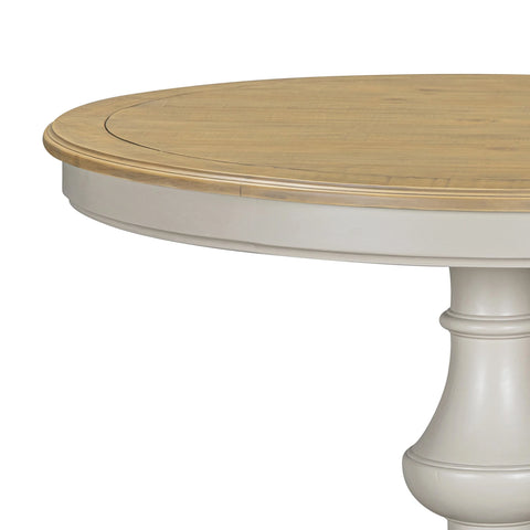 Close-up of a Chateau round dining table showing a light natural wood top and Grey pedestal base against a white background. 