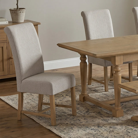 A dining room scene showing a light oak wood table with upholstered dining chairs. 