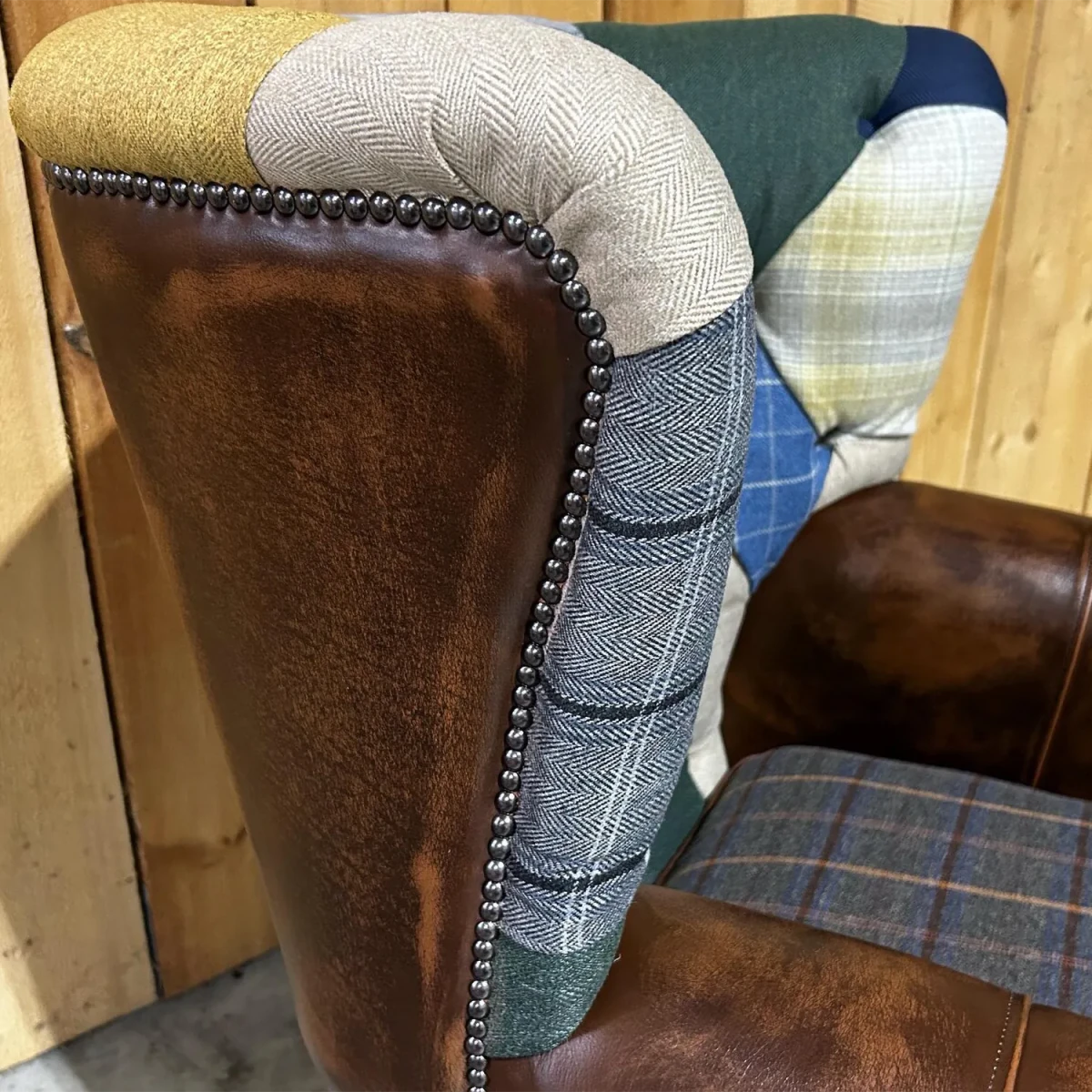 Close up of Cotswold Coloured Patchwork with Antique Tan Leather High Round Back Wing Chair